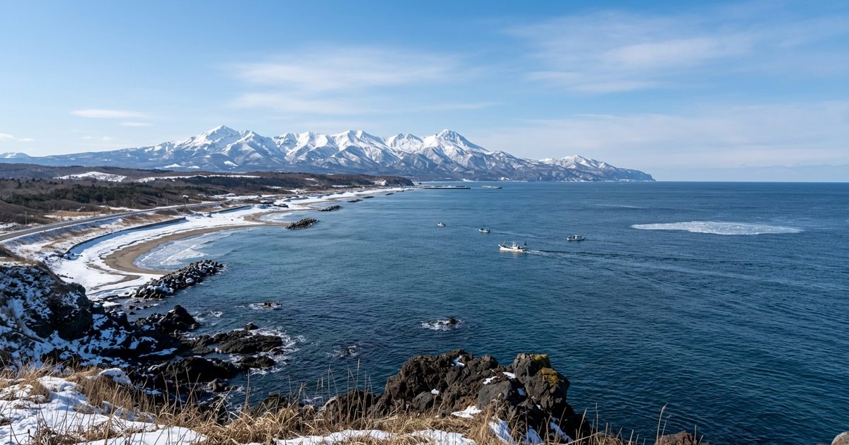 オホーツク海の海岸と、遠くに見える雪をかぶった知床の山並み